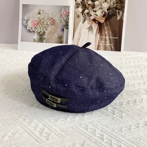 Detail of dark blue denim beret with white star dots and double metal buckle leather strap