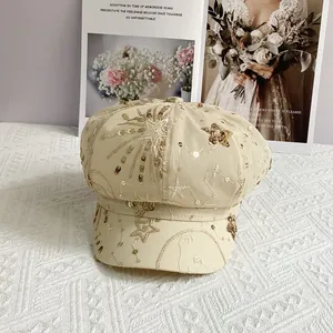 Detail of beige newsboy hat with mesh overlay, gold sequins and star embroidery