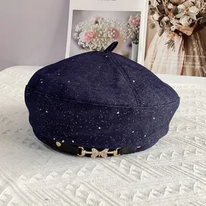 Close-up of a dark blue denim beret with star-like glitter and a rhinestone butterfly buckle