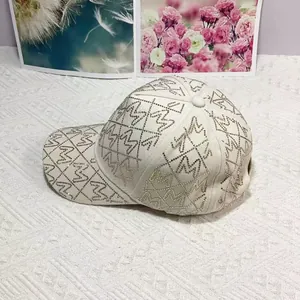 Detail der beigen Baseballkappe mit Strass-M-Buchstaben im Rautenmuster-Design