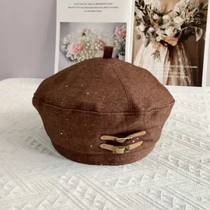 Detail of dark brown beret with star glitter texture and leather strap buckle