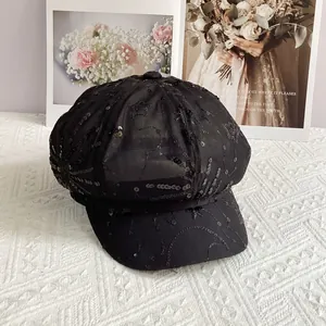Close-up of stylish black sequin mesh newsboy hat on a textured white fabric