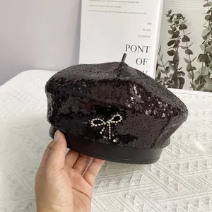 Détail du béret à paillettes noires avec un nœud en strass étincelant et bordure en cuir