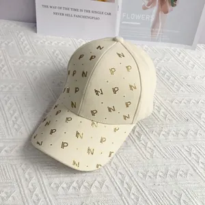 Gros plan sur casquette beige avec motifs de lettres P et N en strass étincelants