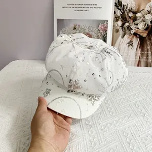 Detail of white newsboy cap with silver sequins and embroidered star patterns