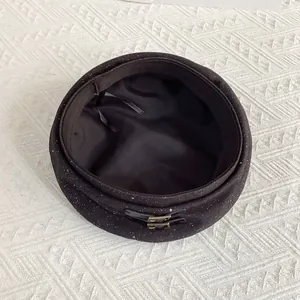 Detail of glitter black beret with leather buckle accents and adjustable inner strap