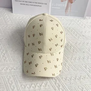 Détail d'une casquette beige avec motifs de lettres scintillantes en strass dorés