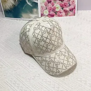 Detail der cremeweißen Baseballkappe mit M-Buchstaben aus Strass und Rautenmuster