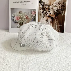 Detail of white newsboy cap featuring shimmering silver sequins in star embroidery patterns
