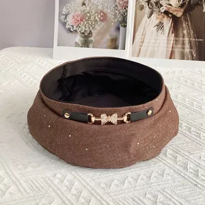 Close-up of brown glitter beret with rhinestone butterfly buckle and black leather strap