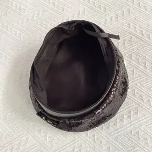 Détail du béret à paillettes noires montrant la texture brillante et le bord en cuir
