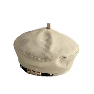 Beige glitter beret hat with a rhinestone butterfly chain buckle on a black strap