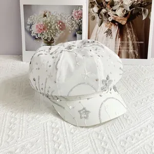 Close-up of white baker boy hat with silver sequins and star embroidery texture