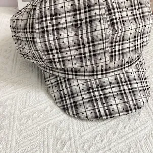 Close-up of black and white plaid newsboy cap with shimmering rhinestone details