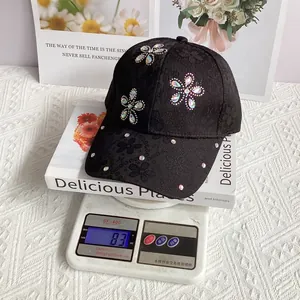 Detailed view of women's black satin baseball cap with floral lace and rhinestone flowers