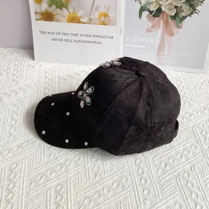 Close-up of black satin baseball cap featuring floral embossing and rhinestone flower details