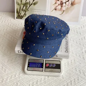 Detail showing deep blue denim newsboy hat with gold studs on a scale weighing 133g