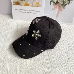 Detailed view of black satin baseball cap with floral lace and colorful rhinestone accents