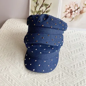 Dark blue denim military flat caps with gold and silver studs on ivory background