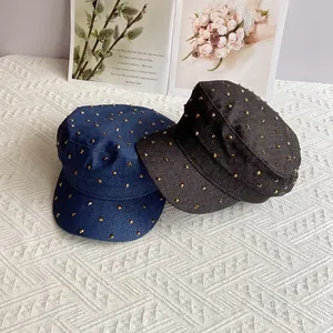 Flat top denim military caps with gold rivet studs on white background and magazine