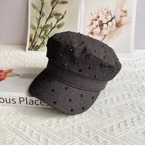 Detail of dark denim baker boy hat featuring dense black conical studs on the crown