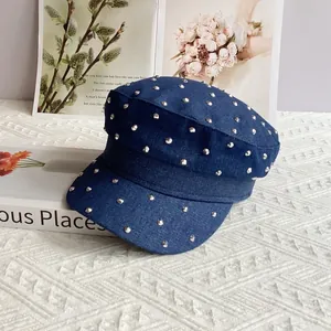 Detail of blue denim cadet cap with sparkling silver studs on a textured white surface