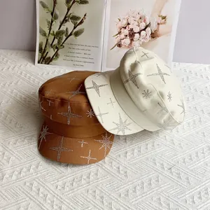 Gros plan de casquettes plates marron et beige avec motifs d'étoiles en strass