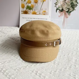 Detail of light brown newsboy cap with woven cotton-linen texture and leather buckle strap