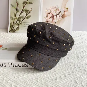 Detail of dark denim military cap featuring dense gold metal conical studs and rivets