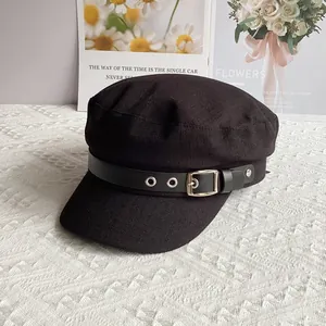 Detail of a vintage black baker boy hat featuring a leather strap and silver buckle