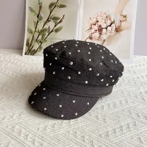 Detail of black denim military cap featuring silver cone studs and textured metal accents
