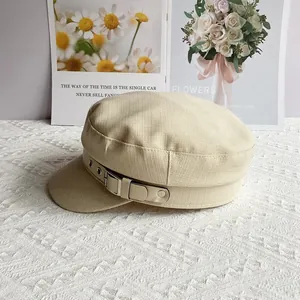 Detail of beige newsboy hat featuring leather strap, silver metal buckle and soft fabric