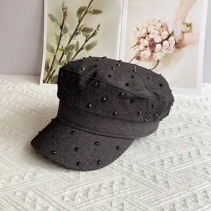 Close-up of black denim cadet hat with sparkling rhinestones and metal stud details