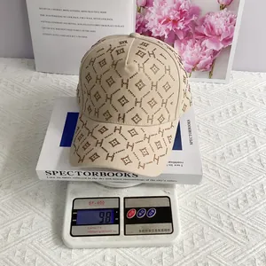 Gros plan sur la casquette beige avec motif H en strass dorés et treillis de diamants