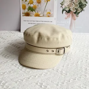 Close-up of beige newsboy hat with textured linen fabric and metal buckle strap detail