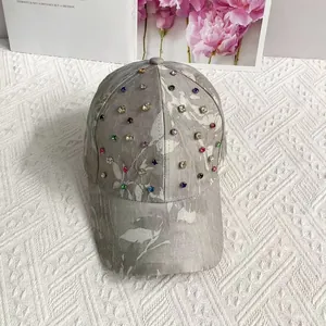 Detail view of colorful rhinestones and leaf prints on a light gray breathable baseball cap