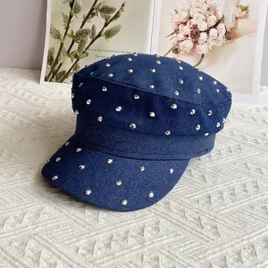 Close-up of navy blue denim newsboy cap with silver studs on textured fabric