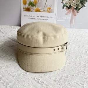 Detail of beige flat-top military hat with cotton linen texture and decorative belt buckle