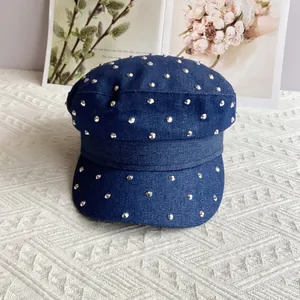Detailed shot of dark blue denim cadet cap with silver studs on textured fabric