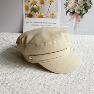 Close-up of beige linen newsboy cap with decorative strap and silver metal rivets detail