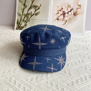 Détails de strass en étoile sur casquette gavroche en denim bleu avec magazine