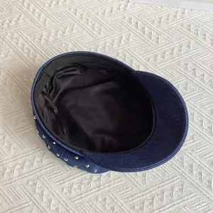 Internal view of denim newsboy cap with black lining and adjustable straps for fit