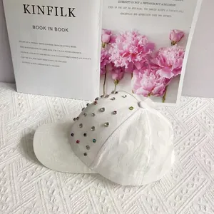 Detail of white baseball cap featuring subtle embossed patterns and colorful rhinestones
