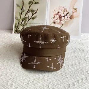 Détail de motifs d'étoiles en strass sur une casquette gavroche marron à sommet plat