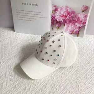 Detail of white baseball cap with colorful rhinestones and textured fabric on a floral backdrop