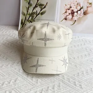 Détail des motifs d'étoiles en strass sur une casquette gavroche élégante crème