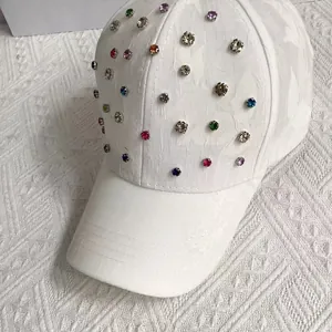 Detailed view of white baseball cap with colorful rhinestones and textured fabric