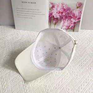 Detailed interior view of white baseball cap showing silver rhinestone studs and metal buckle