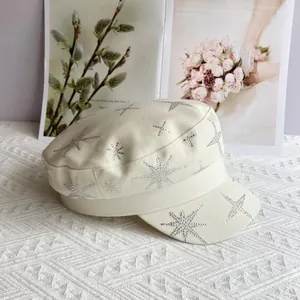 Détail d'un chapeau beige à calotte plate orné de motifs d'étoiles en strass argentés