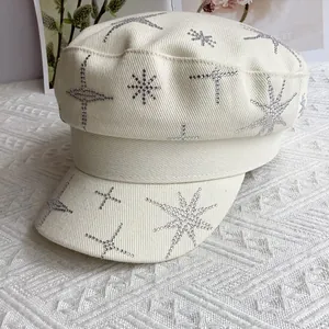 Détail des étoiles en strass scintillants sur le tissu en toile beige de la casquette